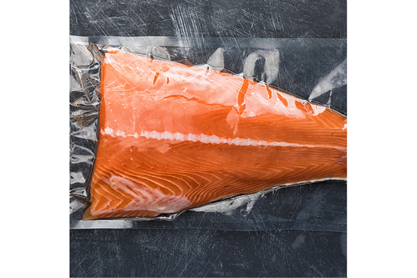 Image Vacuum-packed salmon fillet on dark surface
